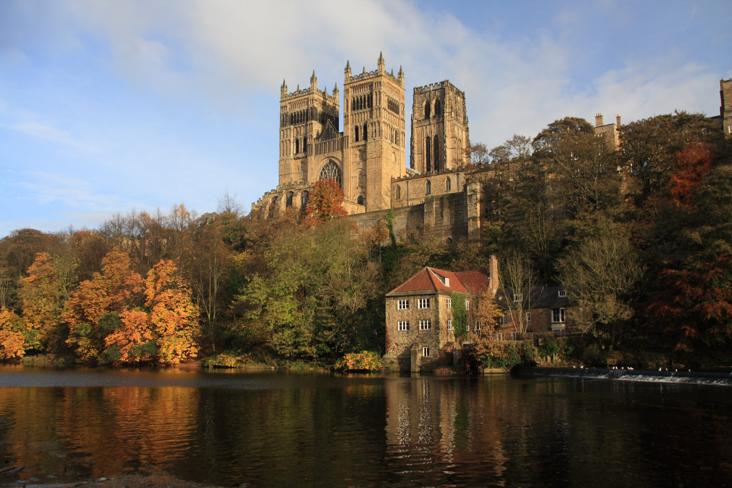 Image of a castle at the top of a hill with trees and a lake underneath in Durham where we provide Pat Testing